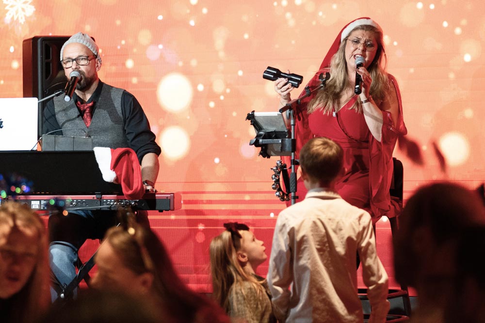 Två personer med julklädsel som uppträder på en scen